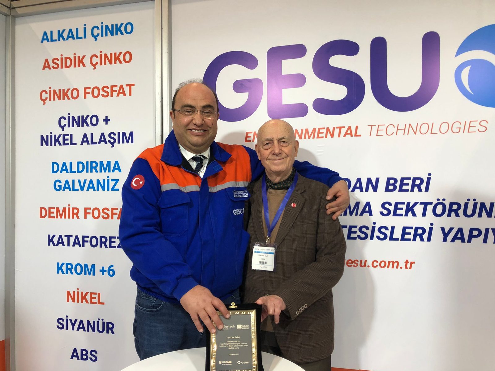TÜYİDER / Artkim plaque presentation at the GESU stand at Surtech Eurasia 2021; a list of plating processes in the background