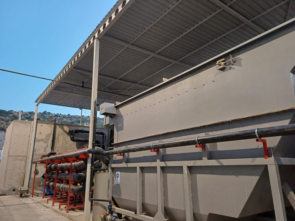 Gelner Gıda arıtma tesisi — saçak altında GESU etiketli gri DAF ünitesi, kırmızı sehpalar üzerinde HDPE borulama ve betonarme havuz duvarı (2023 saha karesi)